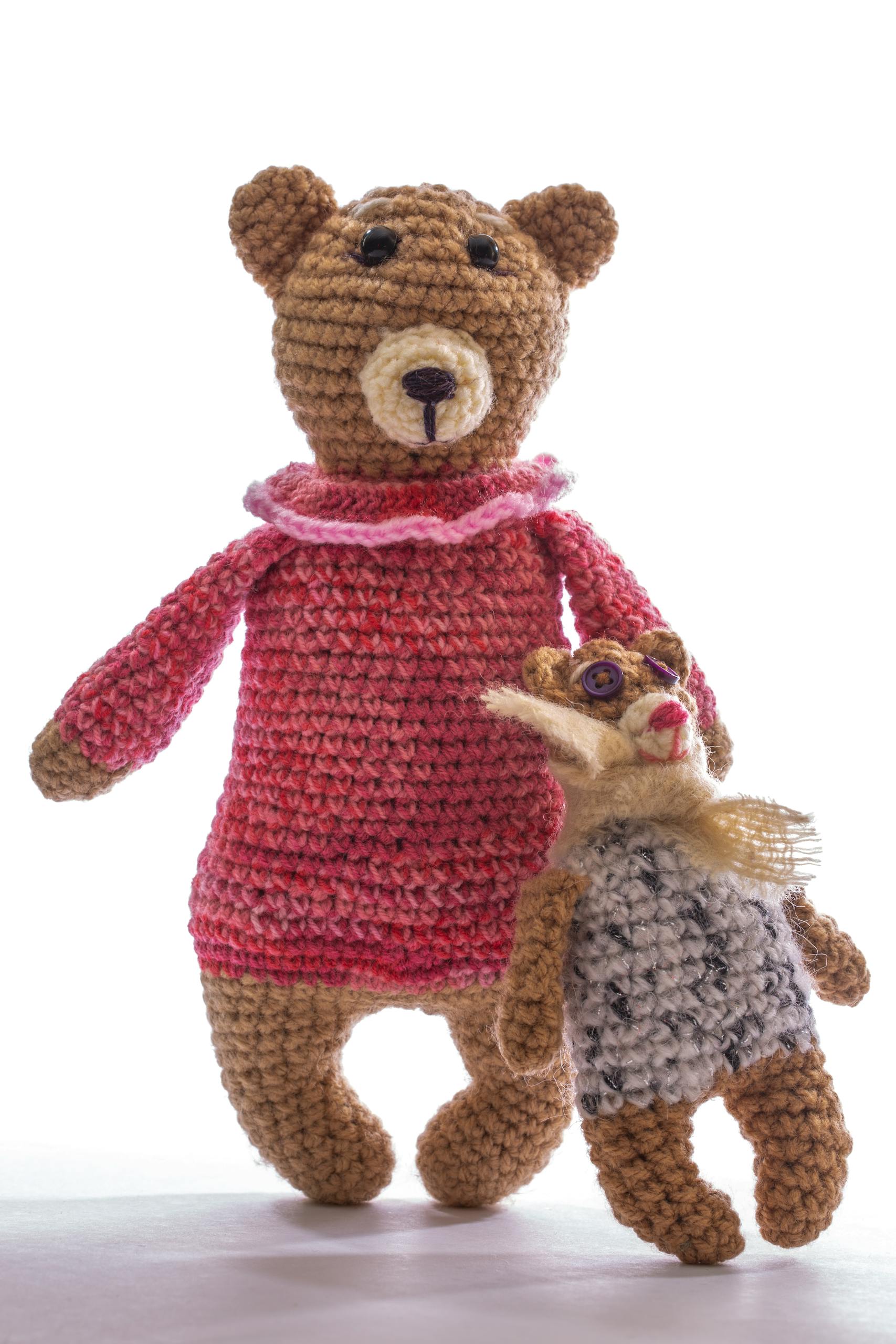 Charming handcrafted crochet bear wearing a pink dress, holding a mini teddy. Perfect for nursery decor.
